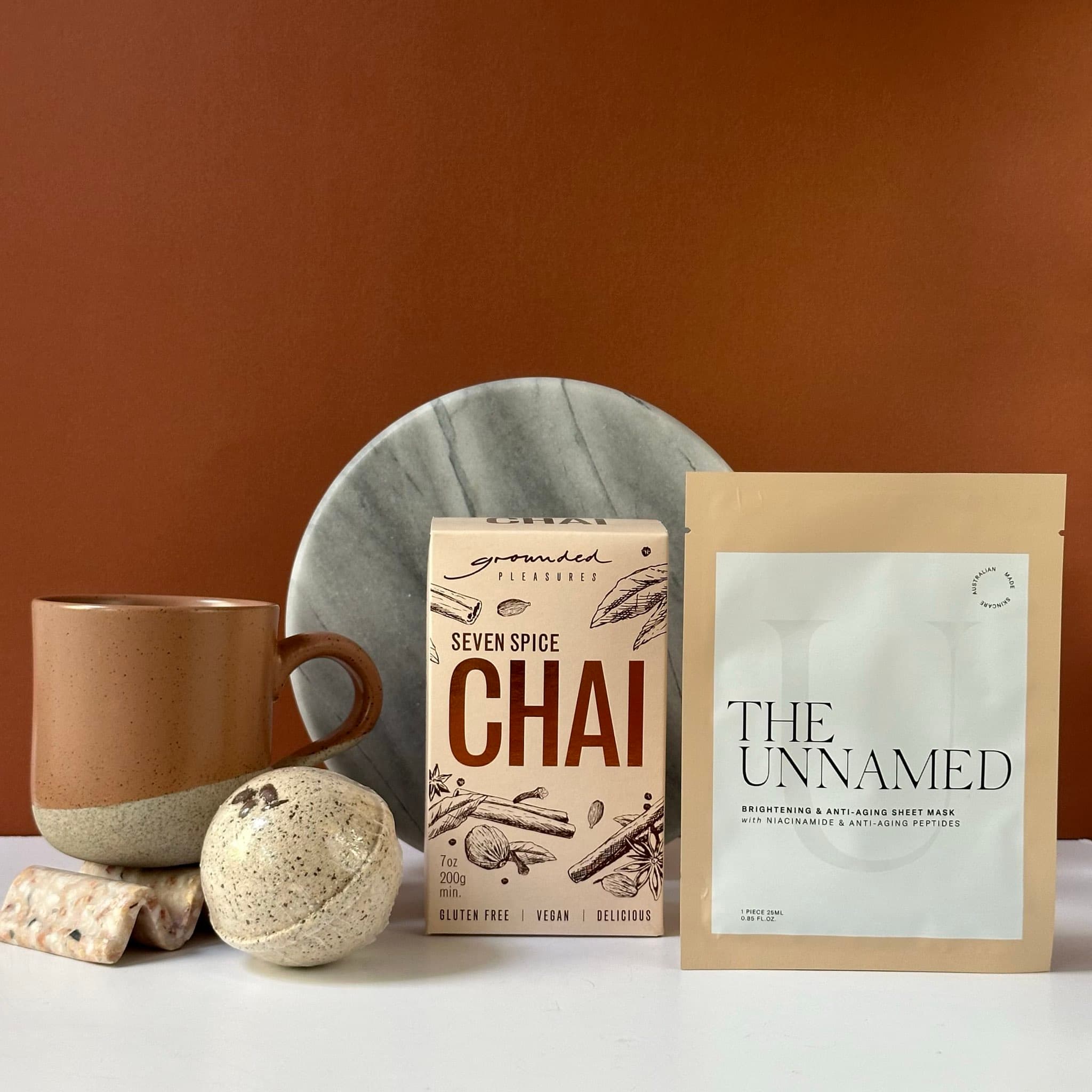 The Calm Chai gift bundle featuring Seven Spice Chai Tea, a Robert Gordon Glaze Mug, Sunday Rose Soy Candle, and Koko Black Salted Caramel Chocolate, beautifully packaged in Thankly’s signature black box.