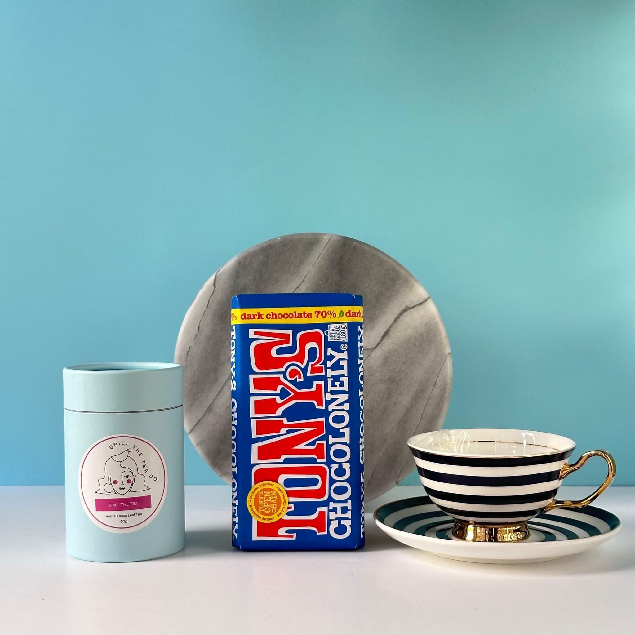 A delightful gift set featuring a fine china tea cup and saucer, Spill the Tea blend, and Tony’s Chocolonely dark chocolate, elegantly packaged in a premium Thankly black box.