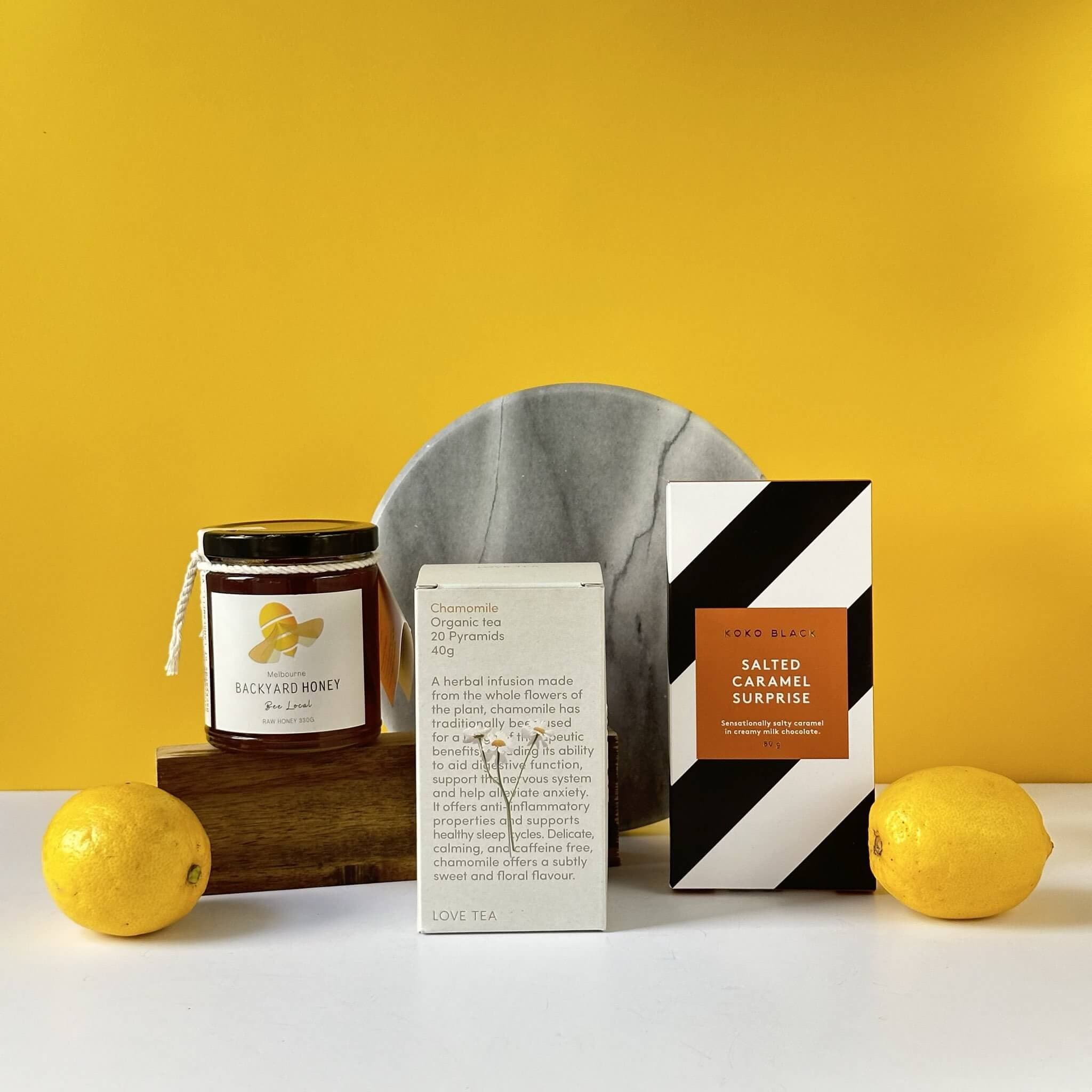 The Sweet Pick Me Up bundle featuring Melbourne Backyard Honey, Love Tea Organic Chamomile Tea, Koko Black Salted Caramel chocolates, and a handwritten Thankly card in a premium black box.